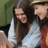 meninas em frente a um tablet rindo ao usar o melhor app para assistir filmes e séries grátis 2022
